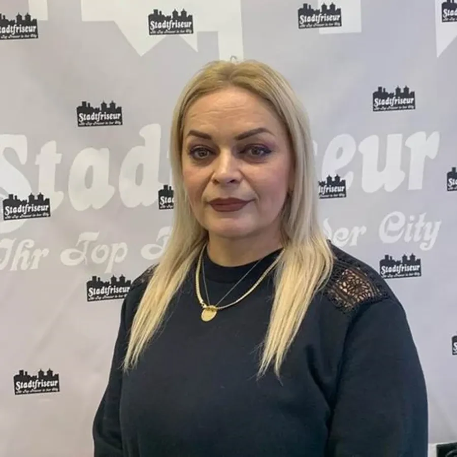 Frau Edita beim Stadtfriseur vor Werbehintergrund