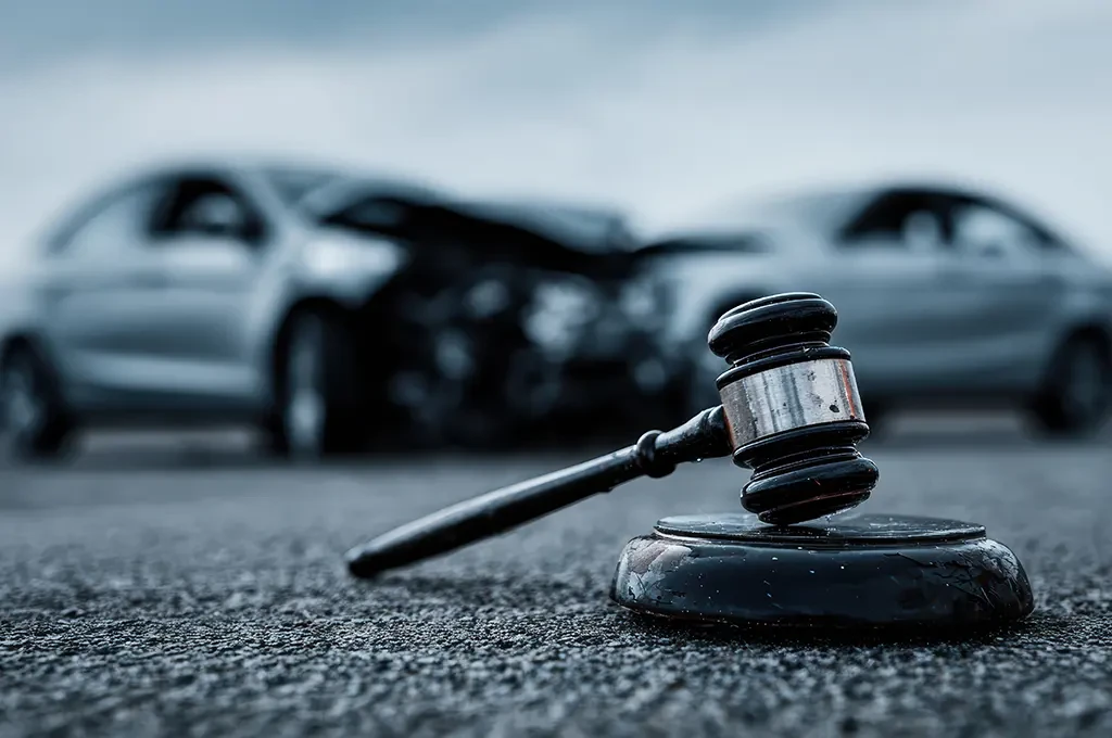 Richterhammer vor Autounfall als Symbol fcr rechtliche Klfrung nach Verkehrsunfall