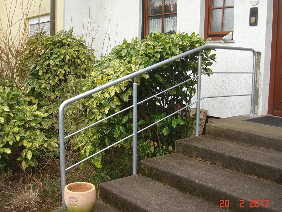 Außentreppengeländer aus Metall für Betontreppe am Hauseingang Außentreppengeländer aus Metall an einer Betontreppe vor einem Wohnhaus