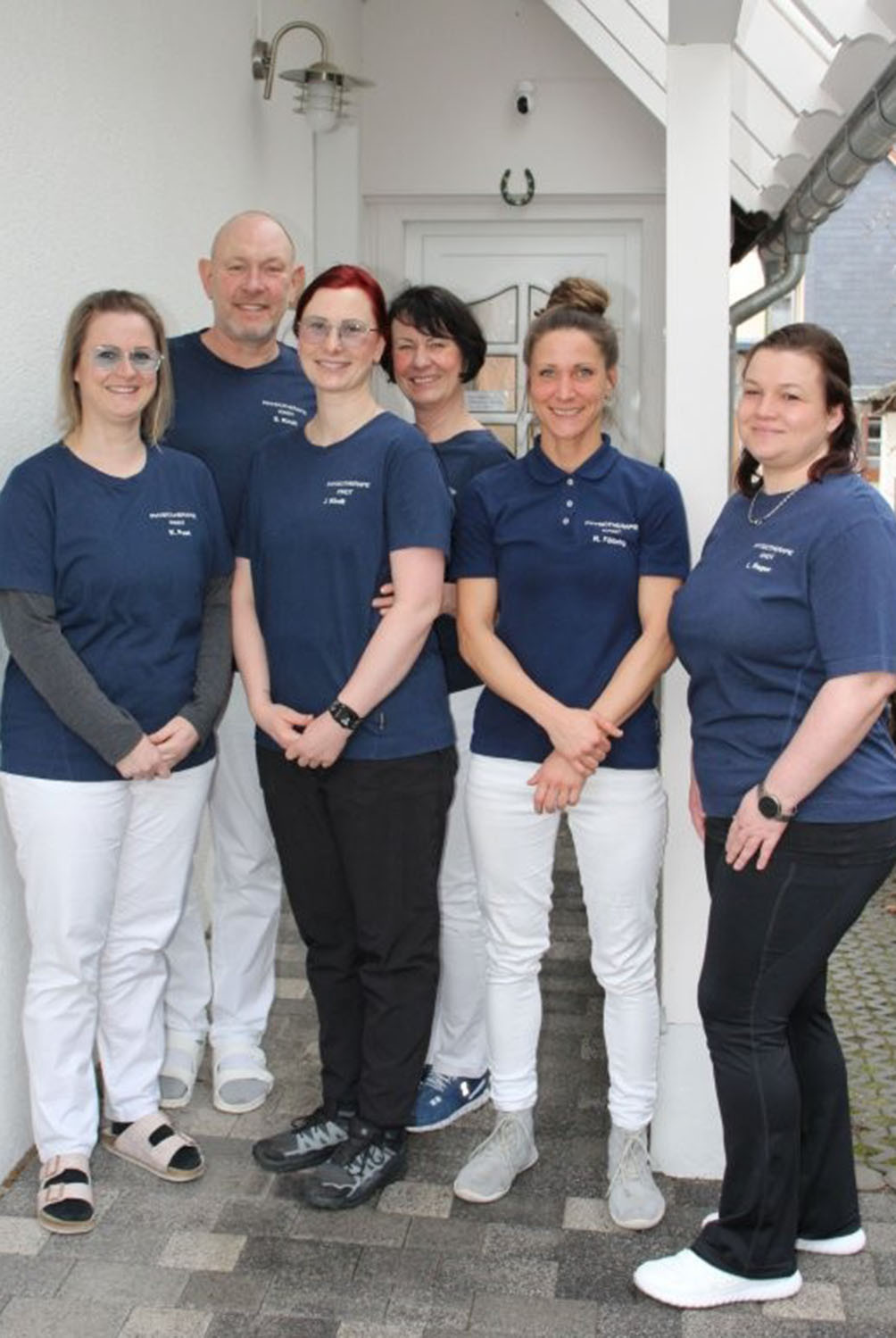 Team der Physiotherapie Favorit in blauer Arbeitskleidung vor der Praxis