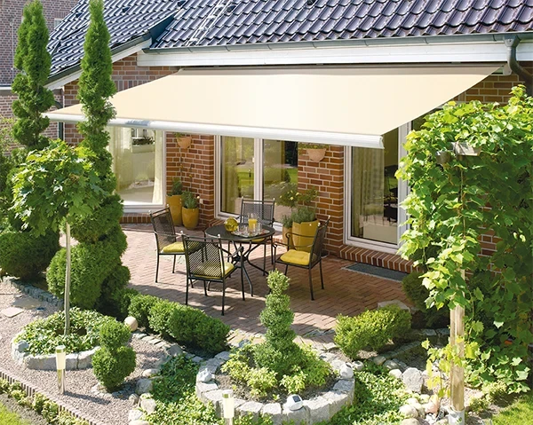 Kadeco Markise auf Terrasse eines Einfamilienhauses mit Gartenmöbeln und gepflegtem Garten