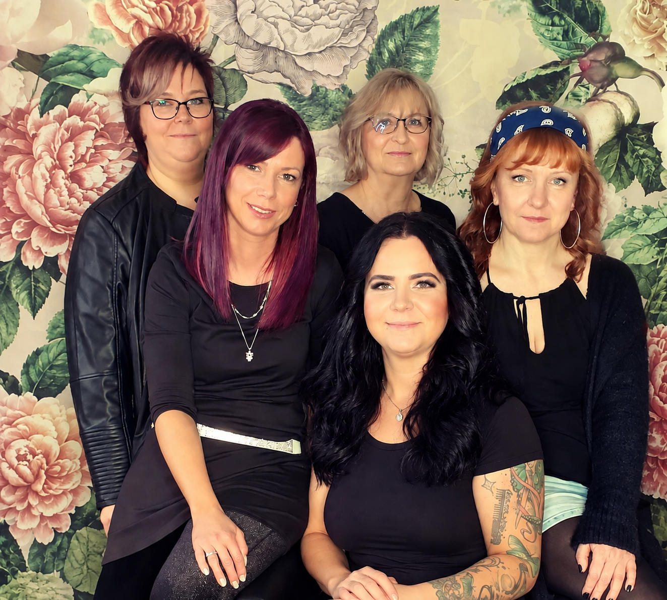 Teamfoto von fünf Frauen vor floralem Hintergrund