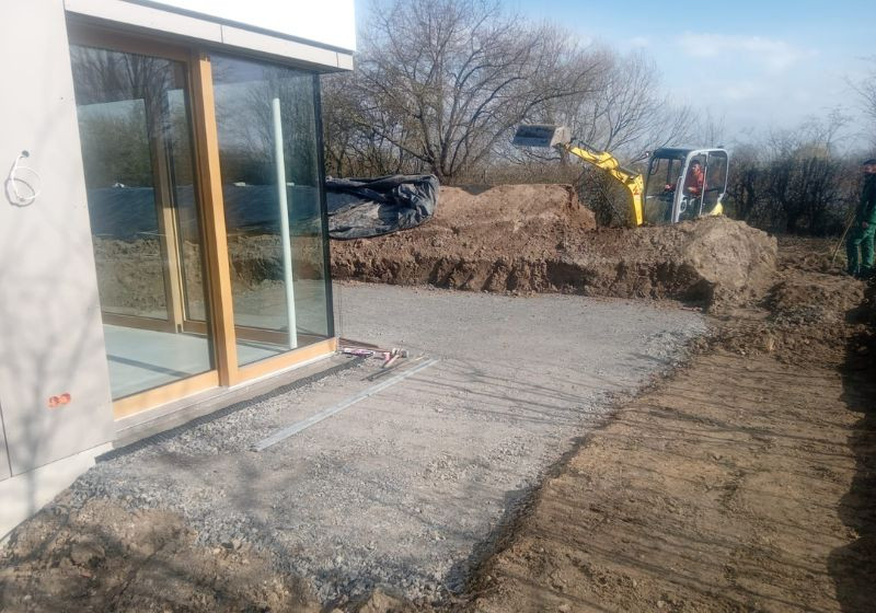 Vorbereitungsarbeiten zum Terrasse bauen in Karlsruhe – vorherige Bauphase mit Bagger und Schotterfläche