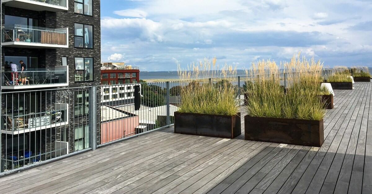Moderne Dachterrasse mit Holzboden, Pflanzkübeln und Ausblick auf die Stadt