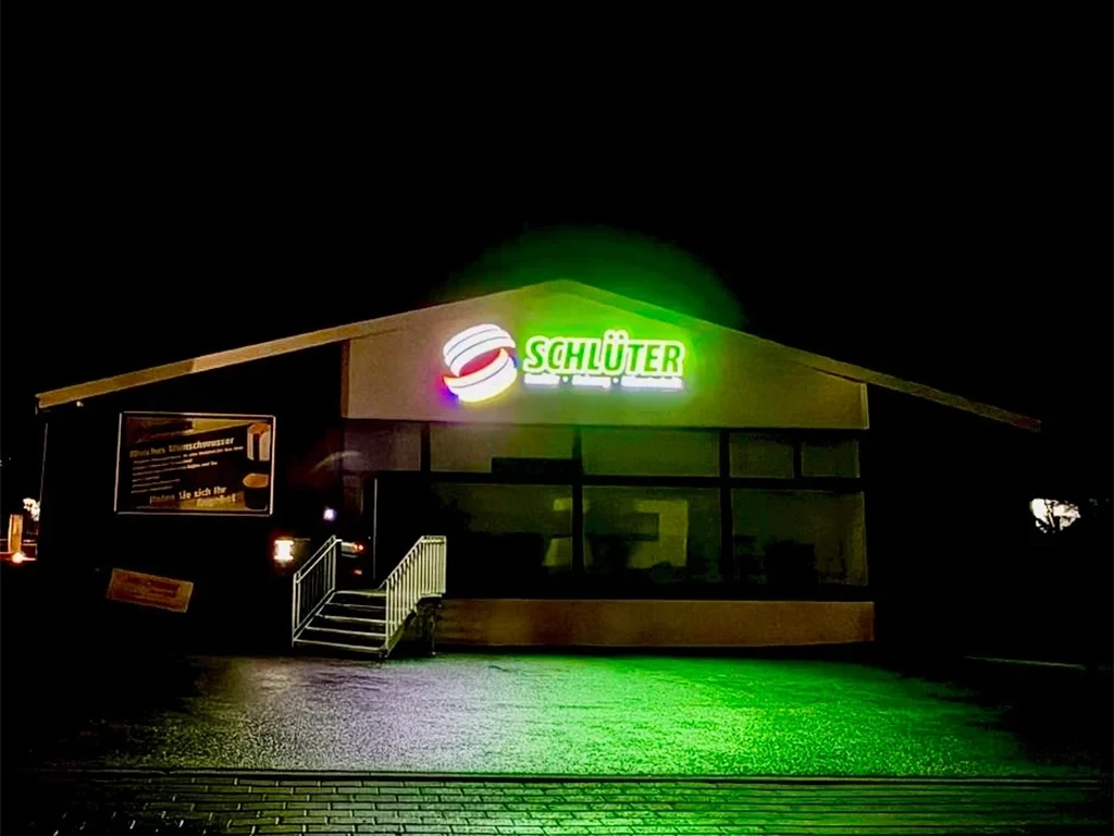 Beleuchtetes Gebäude der Firma Schlüter bei Nacht mit grünem Licht