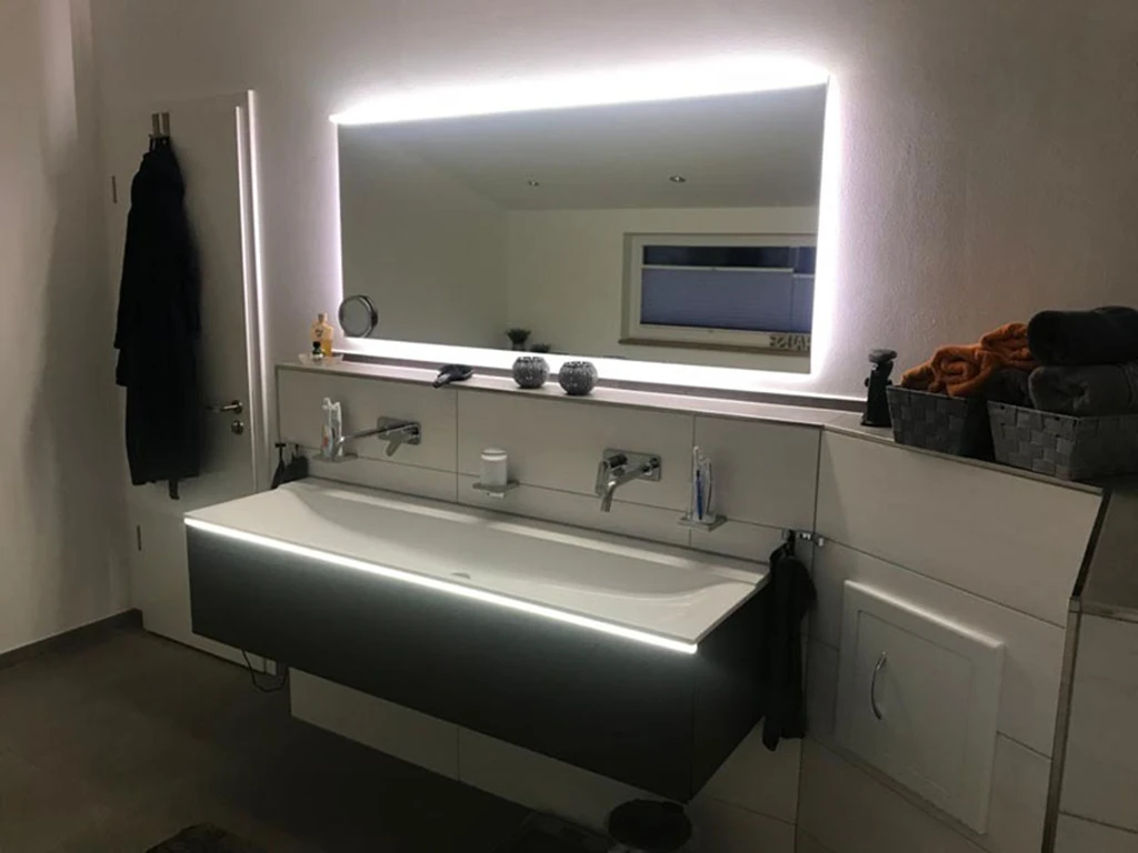 Modernes Bad mit LED-Beleuchtung am Spiegel und Waschbecken