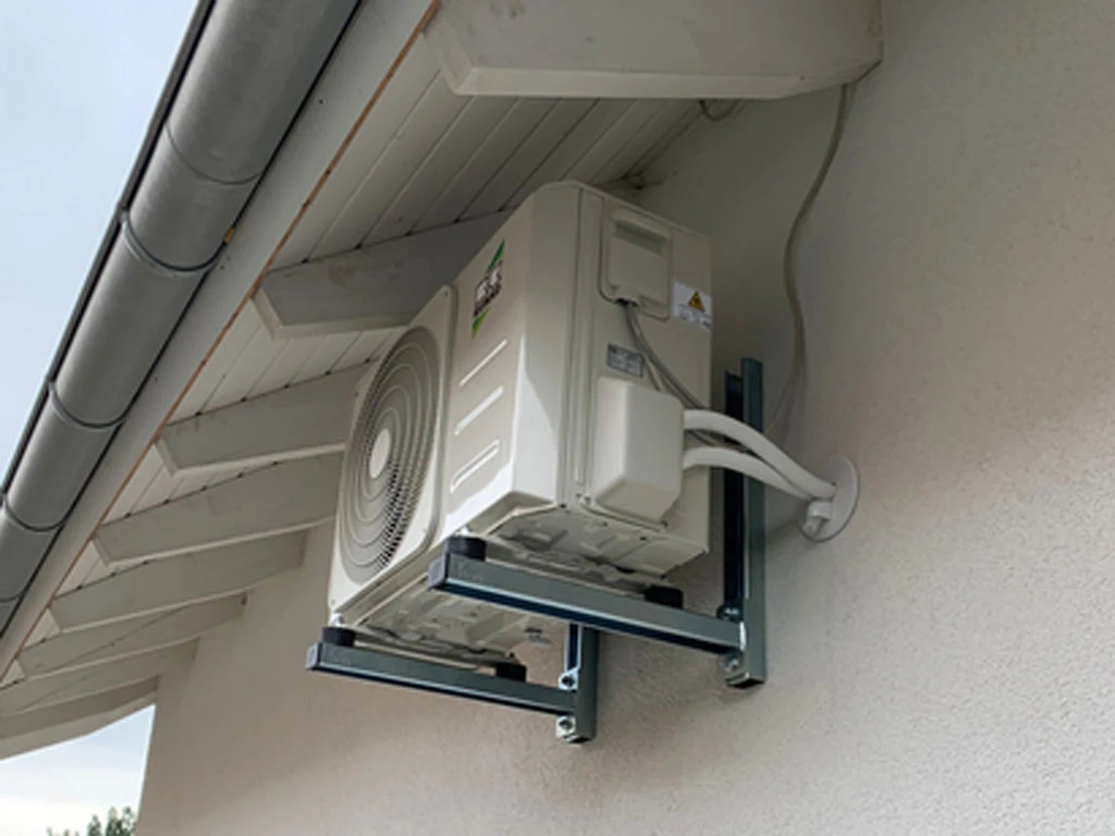 Außenmontage einer modernen Klimaanlage an einer Hauswand unter dem Dach