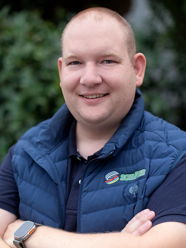 Daniel Schlüter mit blauer Schlüter-Weste vor grünem Hintergrund