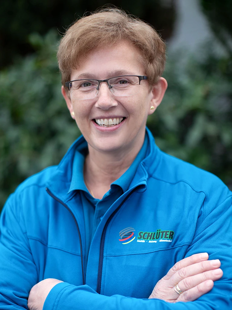 Anja Kruse im blauen Schlüter Arbeitsoutfit vor grünem Hintergrund