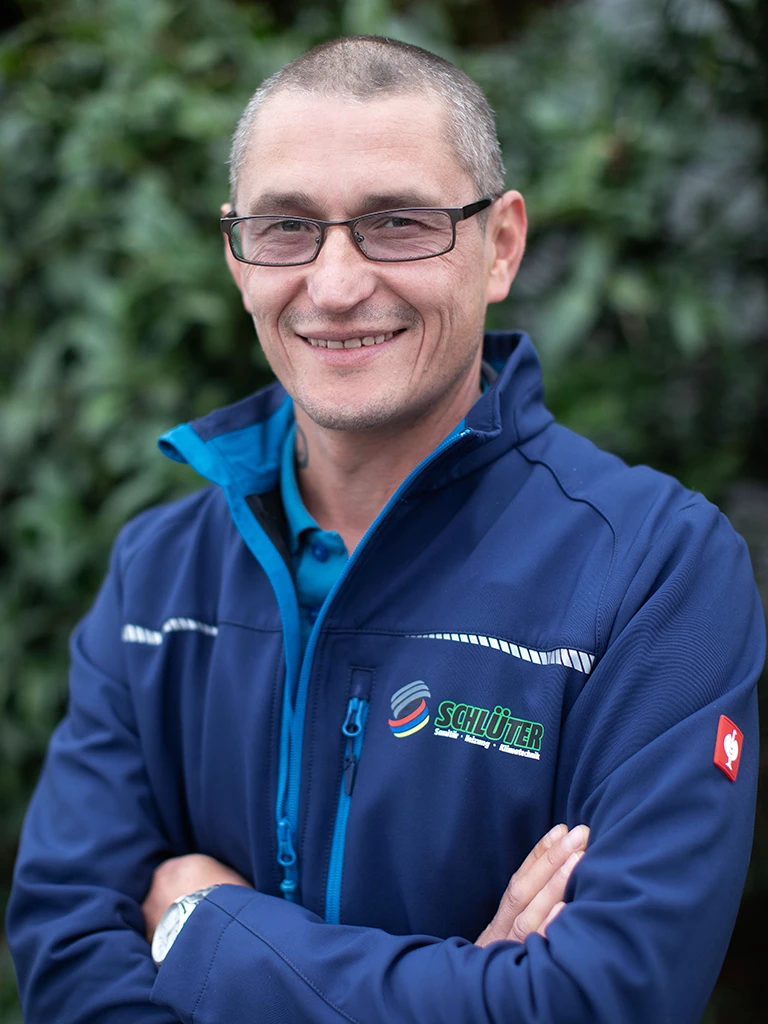 Jevgeni Heidebrecht im Schlüter Arbeitsoutfit vor grüner Naturkulisse