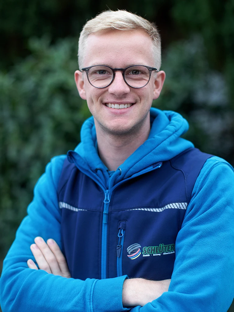 Johannes Steinmeier im blauen Schlüter Arbeitsoutfit vor natürlichem Hintergrund