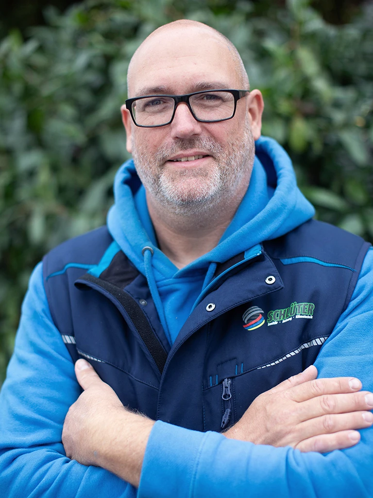 Christopher Bosse in Schlüter Arbeitskleidung vor grünem Hintergrund