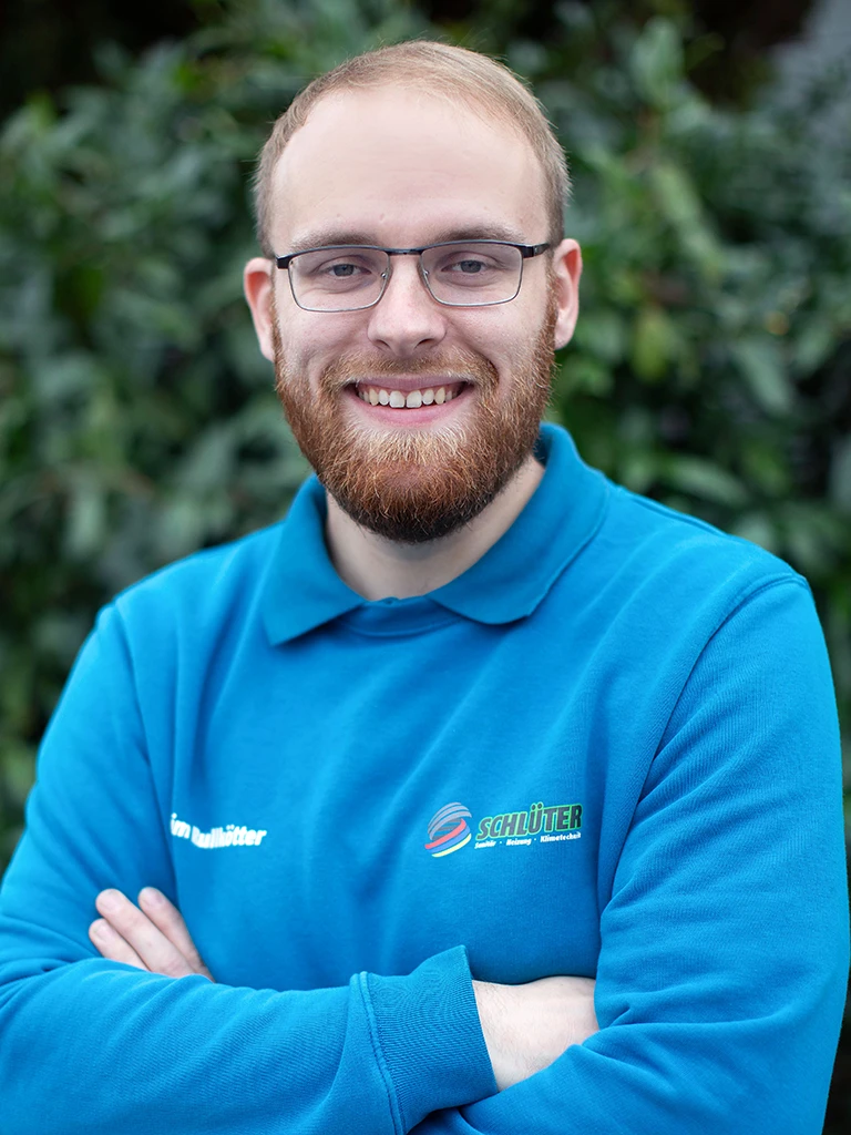 Tim Rullkötter im blauen Schlüter Arbeitsoutfit vor grüner Natur