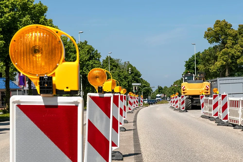 Straßenbaustelle mit Warnbaken und gelben Warnleuchten auf einer Landstraße bei sonnigem Wetter