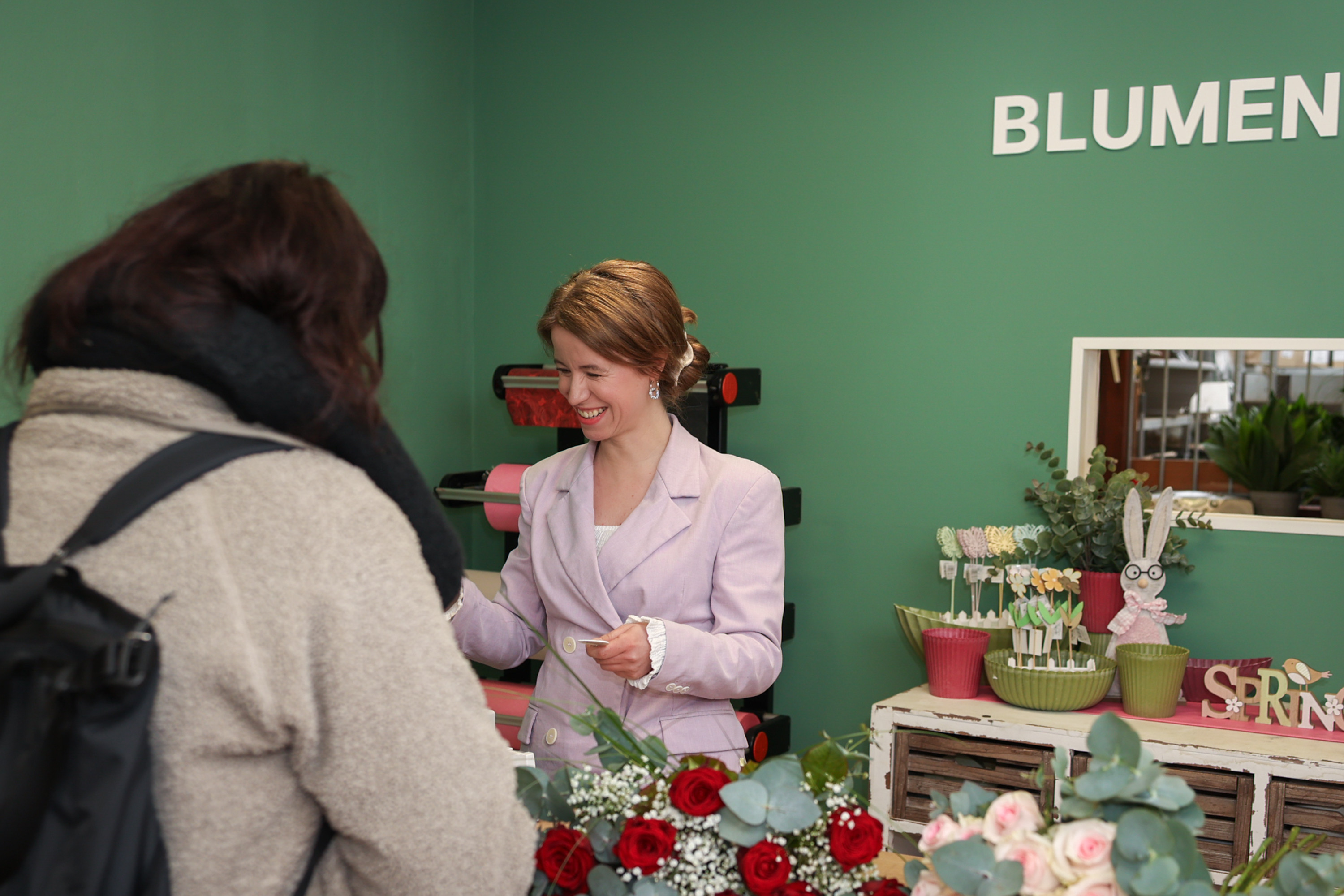 Blumen Wieting Neueröffnung: Floristin berät Kundin im neuen Blumenladen mit frischen Blumensträußen