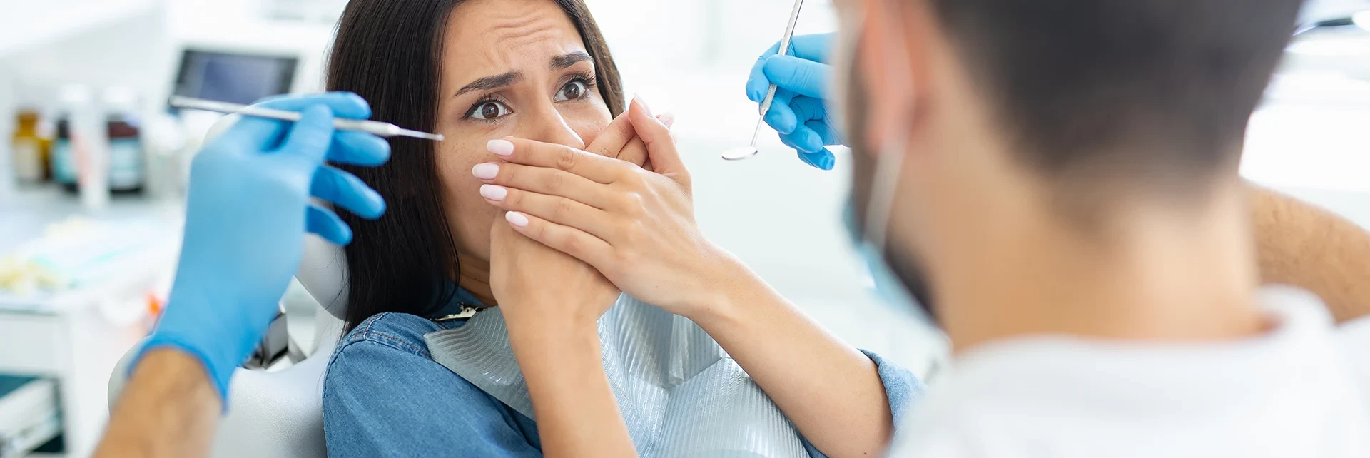 Behandlung eines Angstpatienten beim Zahnarzt Angstpatient beim Zahnarzt hält nervös die Hände, während der Zahnarzt mit Instrumenten arbeitet