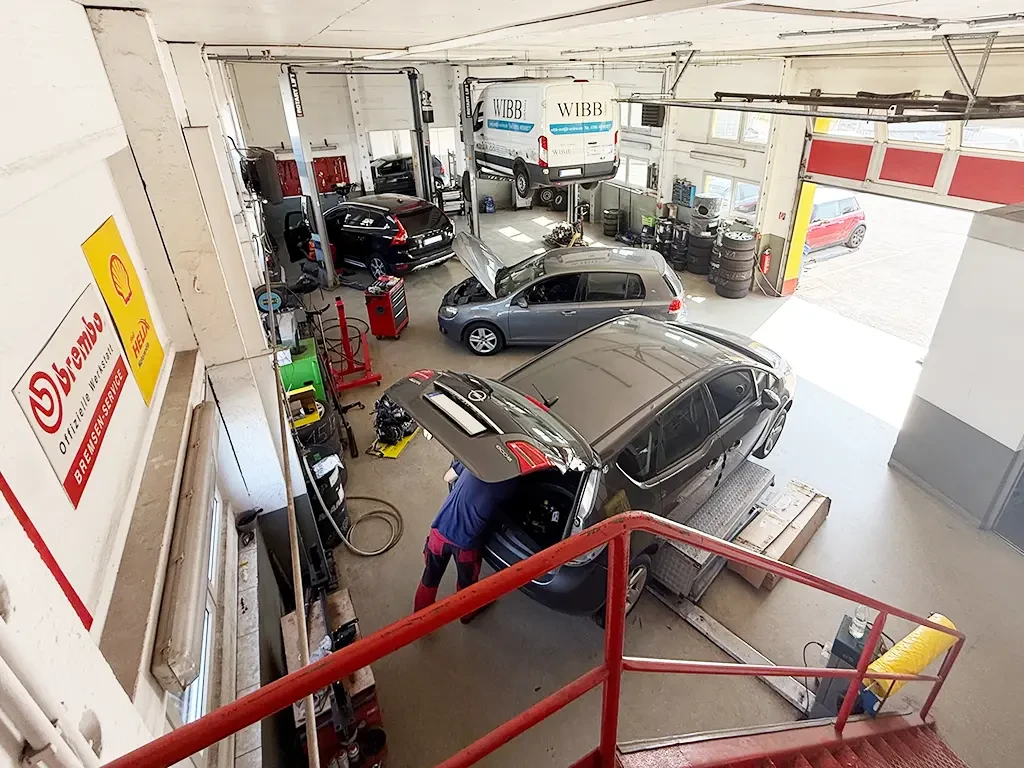 KFZ Meisterservice Werkstatt mit mehreren Autos und Mechaniker bei der Arbeit