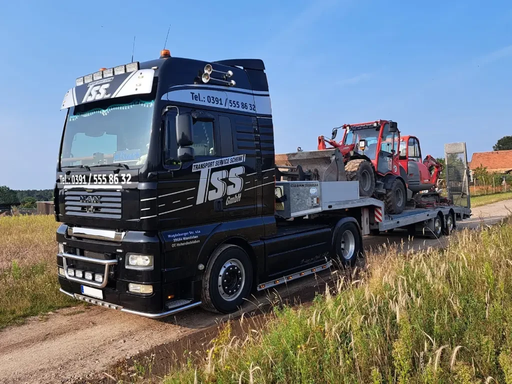 ISS GmbH LKW beim Logistik- und Transportservice für Baumaschinen LKW der ISS GmbH beim Transport von Baumaschinen auf einem Feldweg, Logistik und Transportdienstleistungen