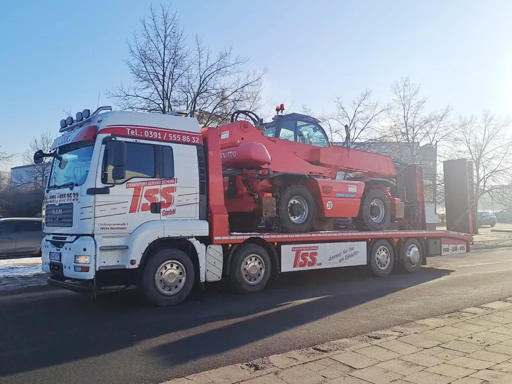LKW von Denis Schenk Logistik transportiert Baumaschine auf offener Straße