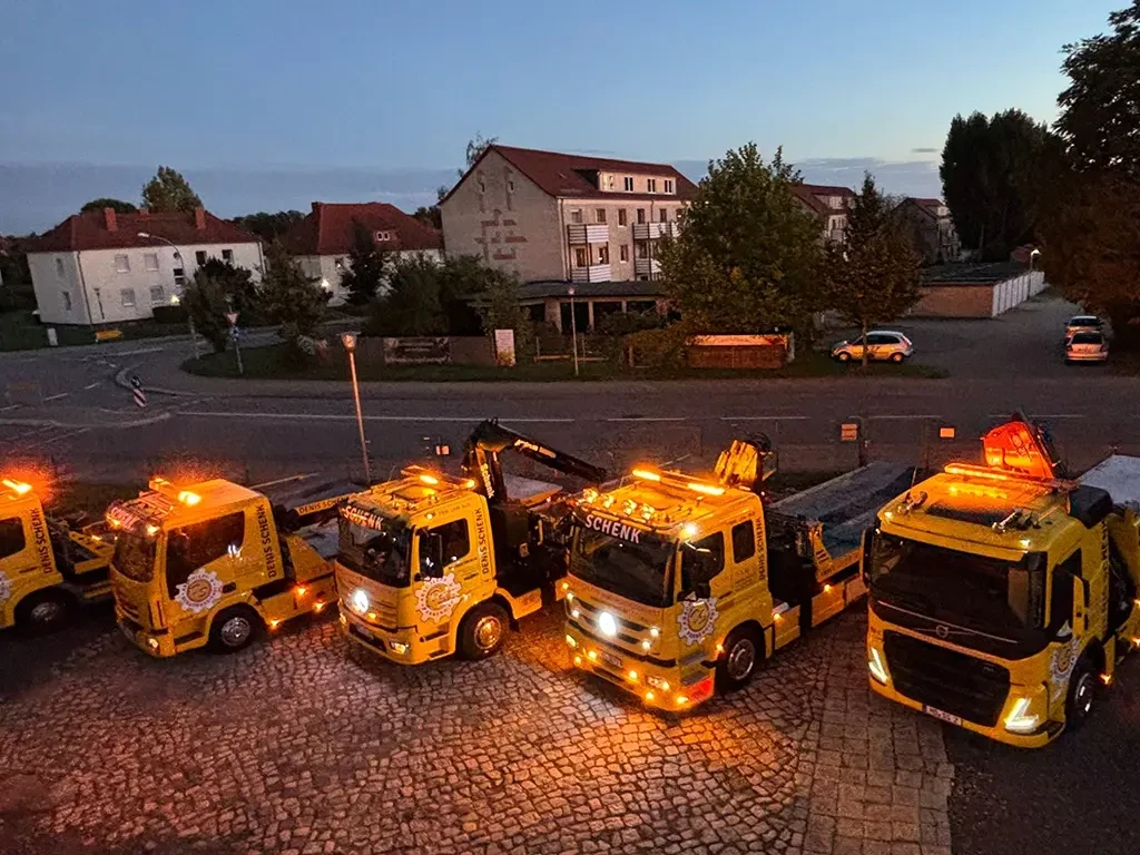Abschleppwagen-Flotte von Dienst Schenk bei Nacht mit eingeschaltetem Warnlicht