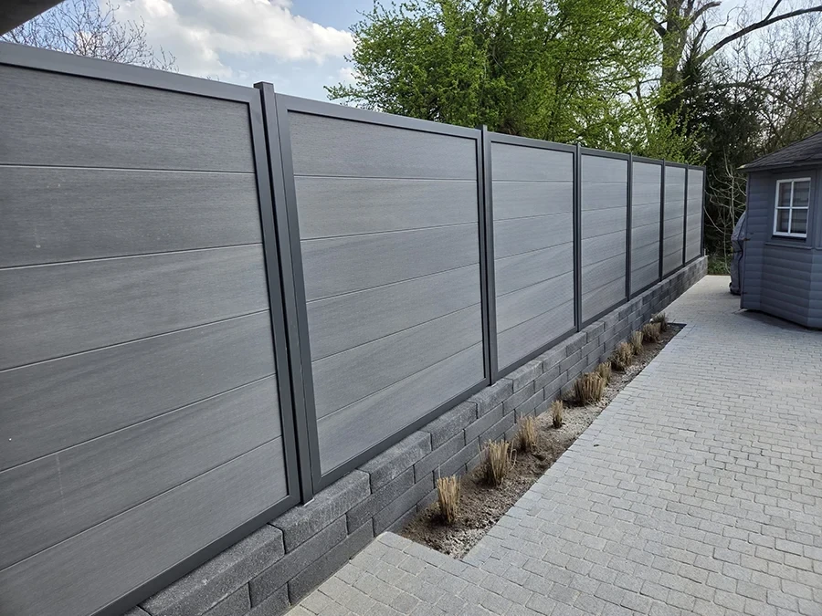 Moderner Sichtschutzzaun als Referenz von CW Partnerputz, montiert auf einer Mauer mit Pflasterweg und Bepflanzung