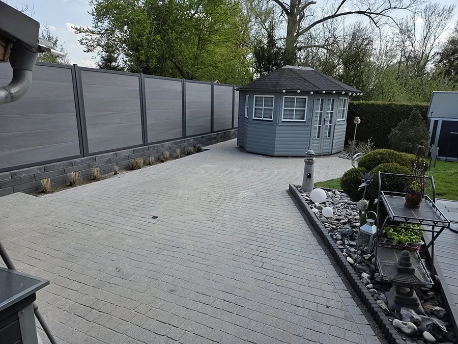 Gepflasterte Einfahrt mit modernem Sichtschutzzaun und Gartenhaus – Referenz von CW Partnerputz