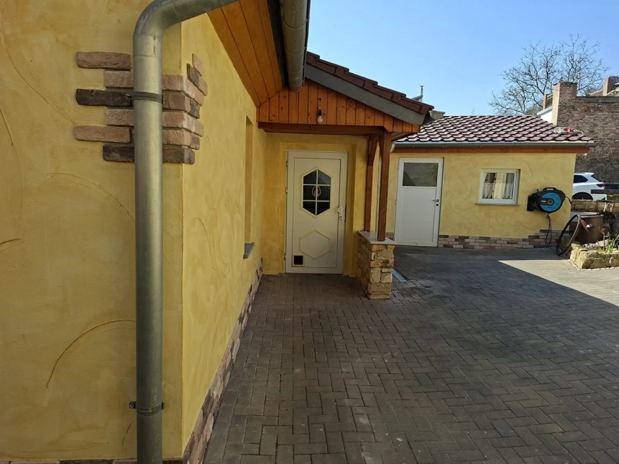 Referenzprojekt von CW Partnerputz: Hausfassade mit gelbem Putz und Steinakzenten