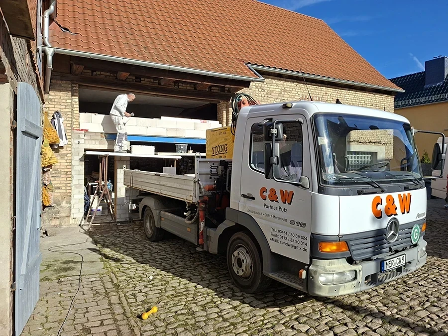 C&W Partner Putz Referenzen – Bauarbeiten an einem Gebäude mit Firmenfahrzeug und Handwerker vor Ort