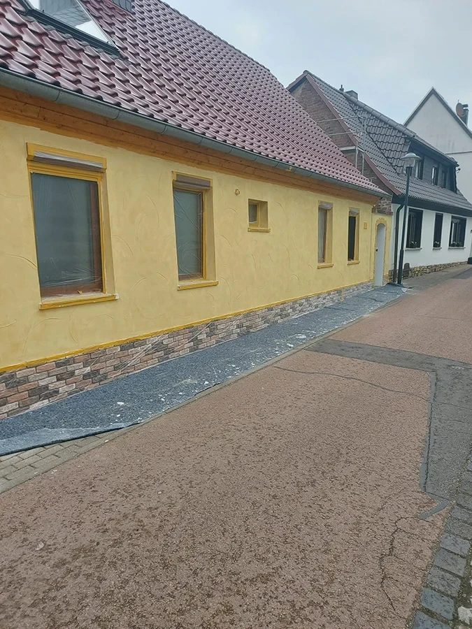 Fassadenrenovierung von cw partnerputz – Referenzobjekt mit gelbem Putz und Klinkeroptik