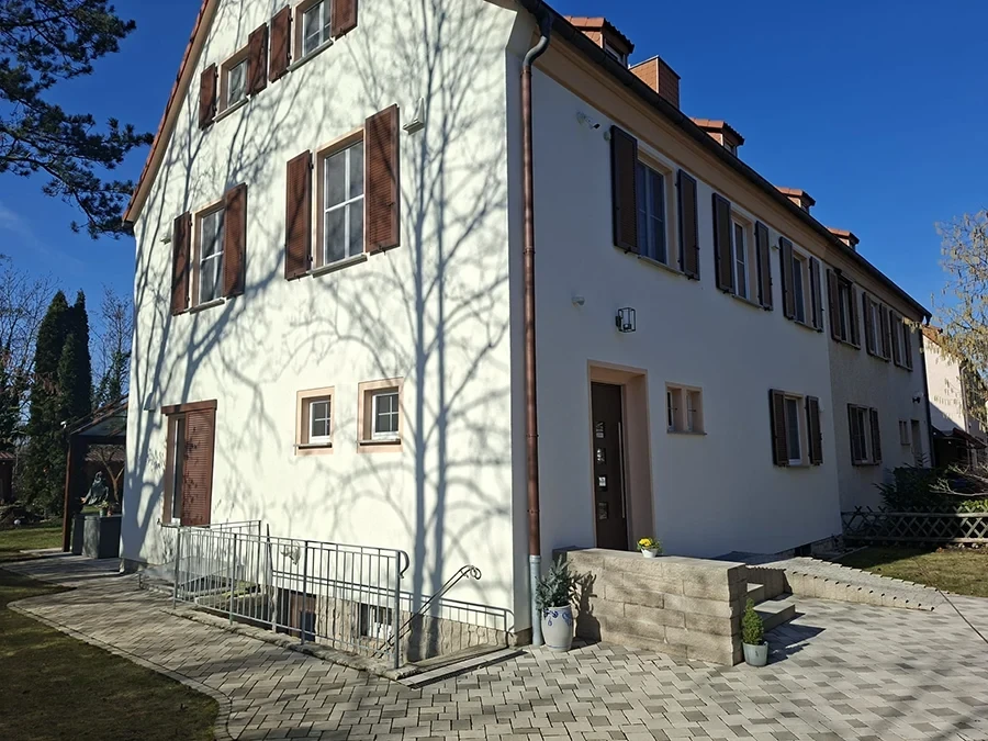 Referenzobjekt von CW Partnerputz: frisch verputztes Mehrfamilienhaus mit hellem Fassadenputz und braunen Fensterläden