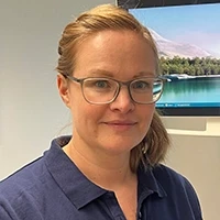 Susann Kuhnigk im Büro mit blauem Hemd vor Bildschirm