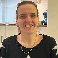 Sandra Wolf in einem modernen Innenraum mit schwarzem Pullover und Kette