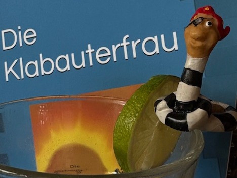 Piratendrink mit Limettenscheibe und Piratenfigur vor blauem Hintergrund