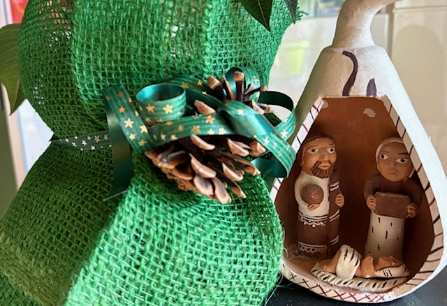 Handgemachte Weihnachtskrippe mit grüner Dekoration und Tannenzapfen