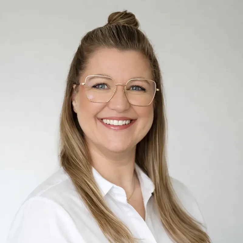 Portrait von Nicole mit langen blonden Haaren und weißer Bluse