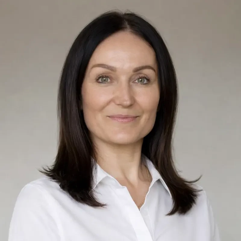 Porträtfoto von Anja W. in weißer Bluse vor neutralem Hintergrund