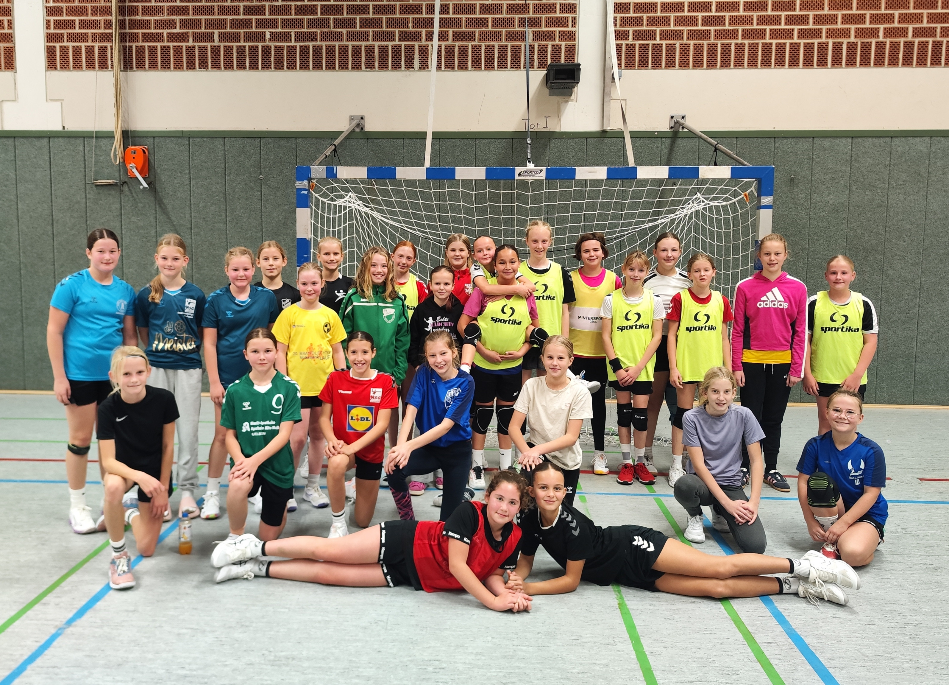 Gruppenfoto der Handball Auswahlmannschaft Jahrgang weiblich 2014 in einer Sporthalle vor einem Handballtor