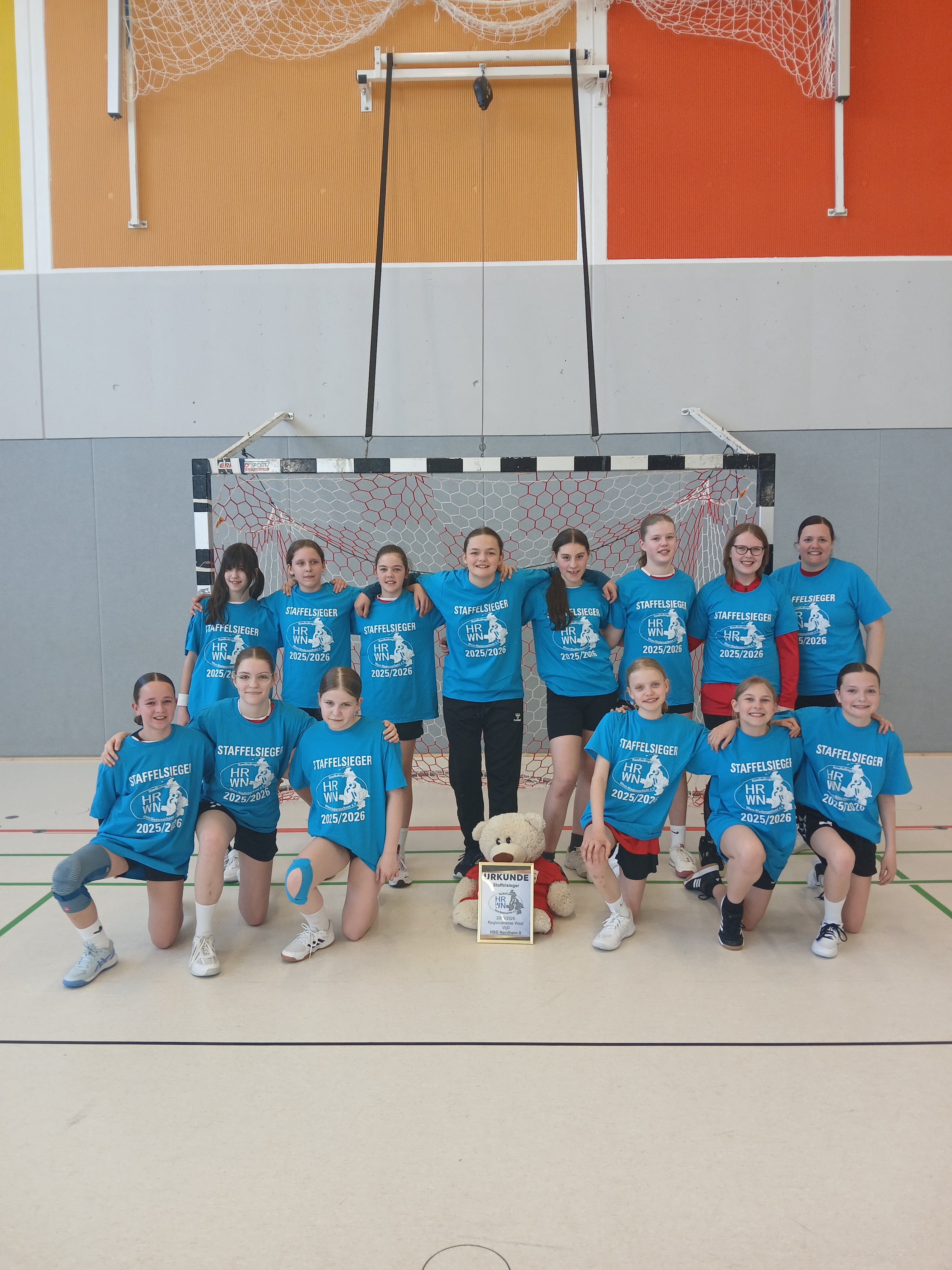 HSG Nordhorn WJD 2 Staffelsieger 2023/2024 Mannschaftsfoto in der Sporthalle vor dem Handballtor mit Urkunde