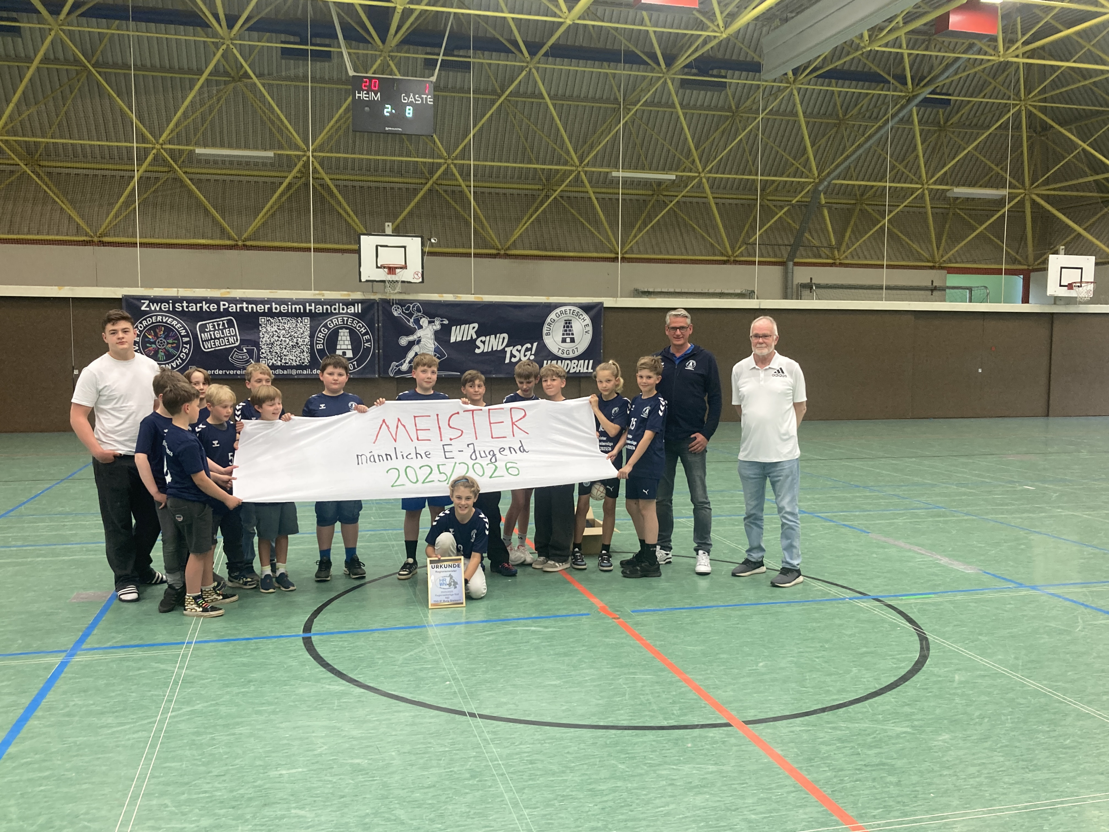 TSG Burg Gretesch männliche E-Jugend Handball Meister 2025/2026 in der Sporthalle mit Trainerteam und Urkunde