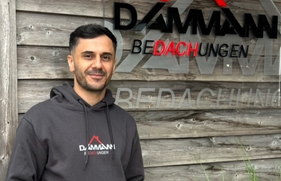 Mitarbeiter des Dachdeckerunternehmens DAMMAX vor Firmenlogo