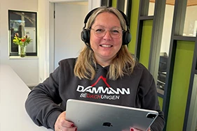 Ulrike Clemens mit Kopfhörern und Tablet im Büro von DAMMANN Bedachungen
