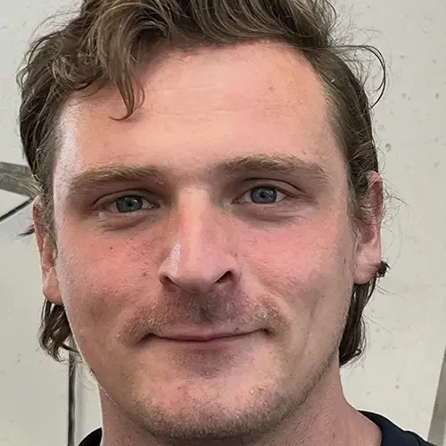 Porträt von Dima mit braunen Haaren vor hellem Hintergrund