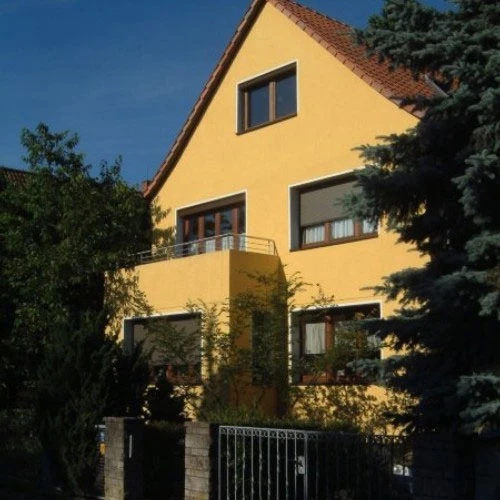 Fassadengestaltung eines gelben Hauses mit Garten