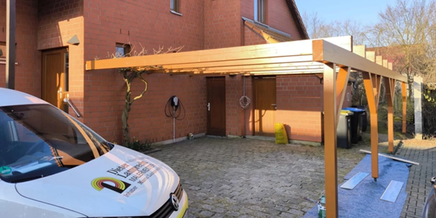 Carport mit Ladestation vor einem Backsteinhaus