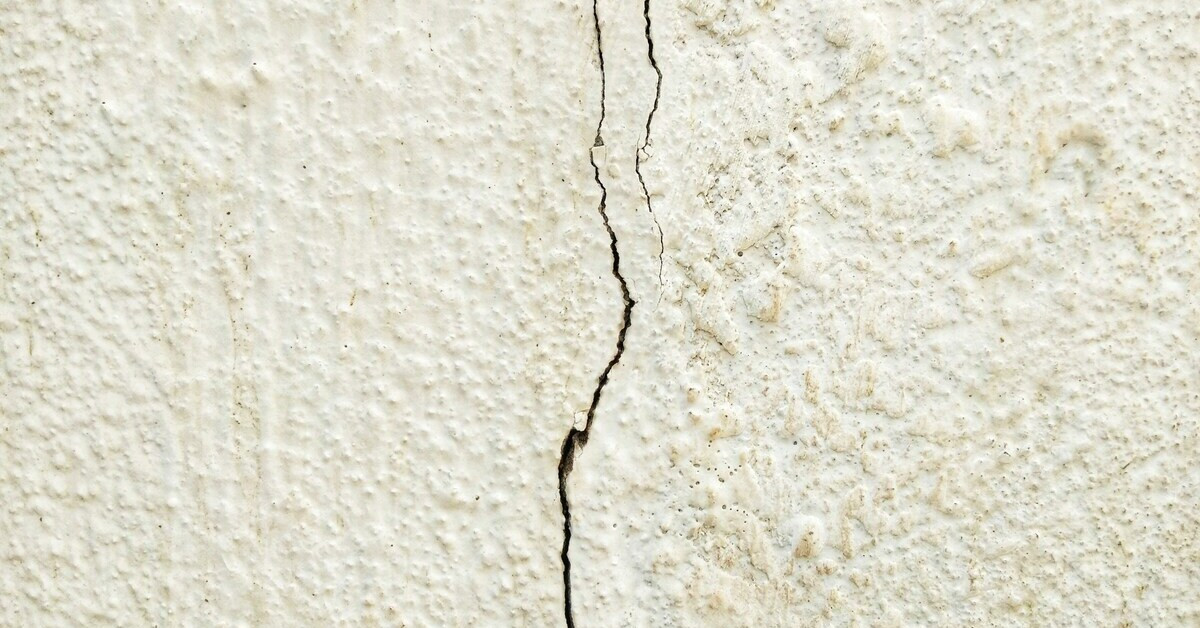 Riss in der Wand – Nahaufnahme eines Wandrisses auf weißer Oberfläche Riss in einer weißen Wand – Nahaufnahme eines Wandrisses