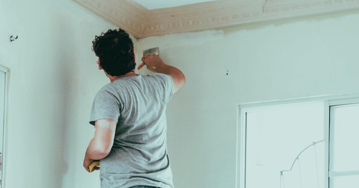 Wohnung selber streichen: Person streicht Wand mit Pinsel