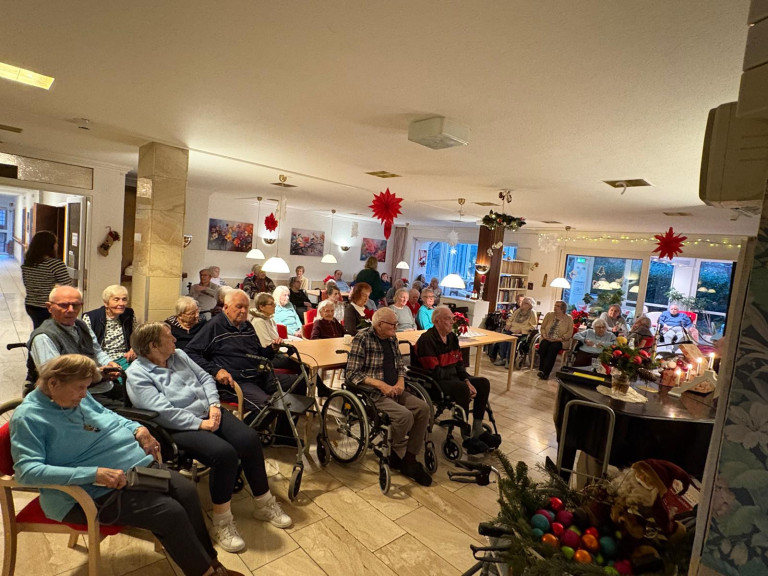 Weihnachtsfeier im Seniorenheim – festlich geschmückter Gemeinschaftsraum mit Senioren Weihnachtsfeier im Seniorenheim mit älteren Menschen in Rollstühlen und festlicher Dekoration