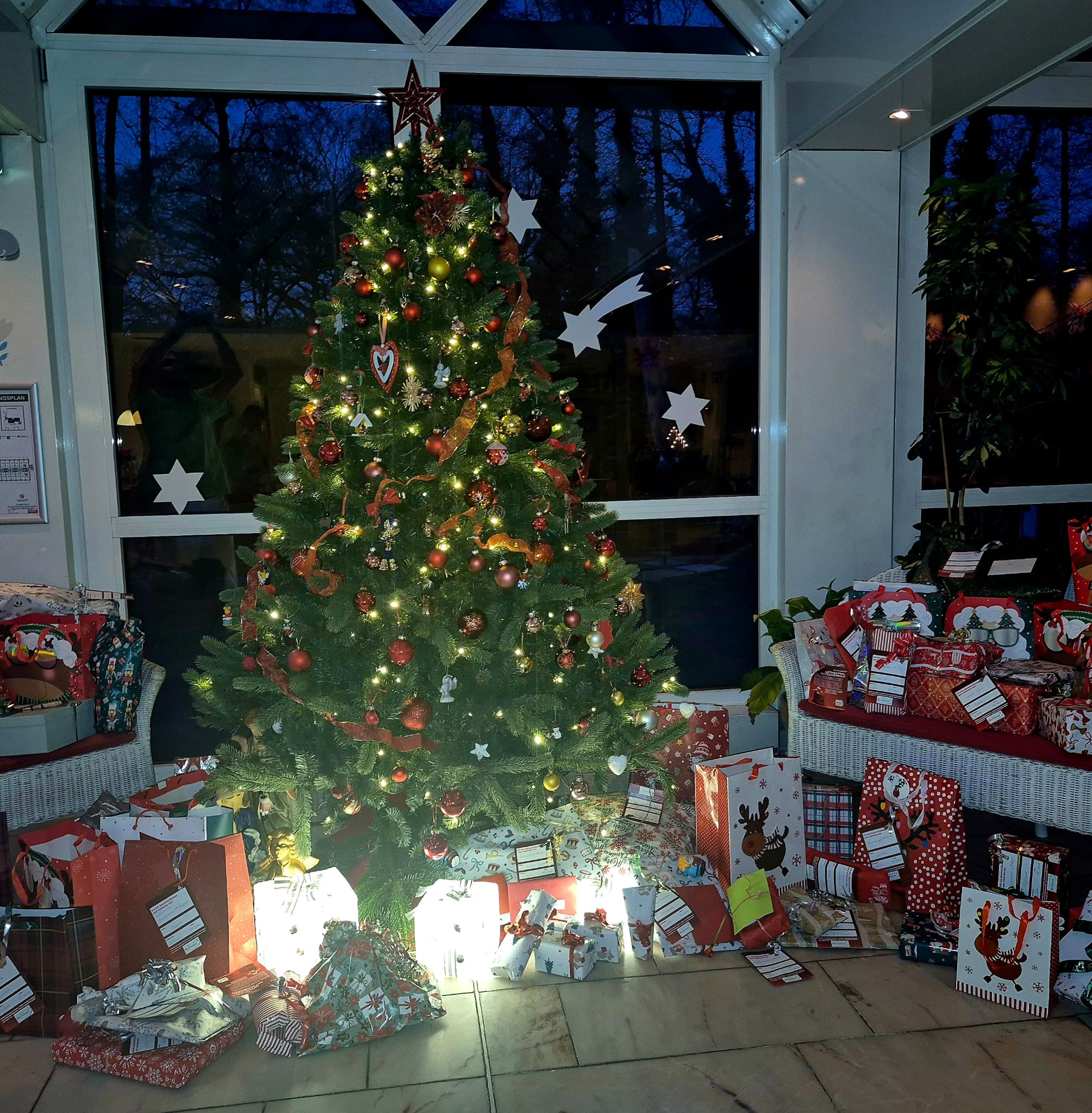 Weihnachtsbaum mit Geschenken im festlich dekorierten Wohnzimmer am Abend