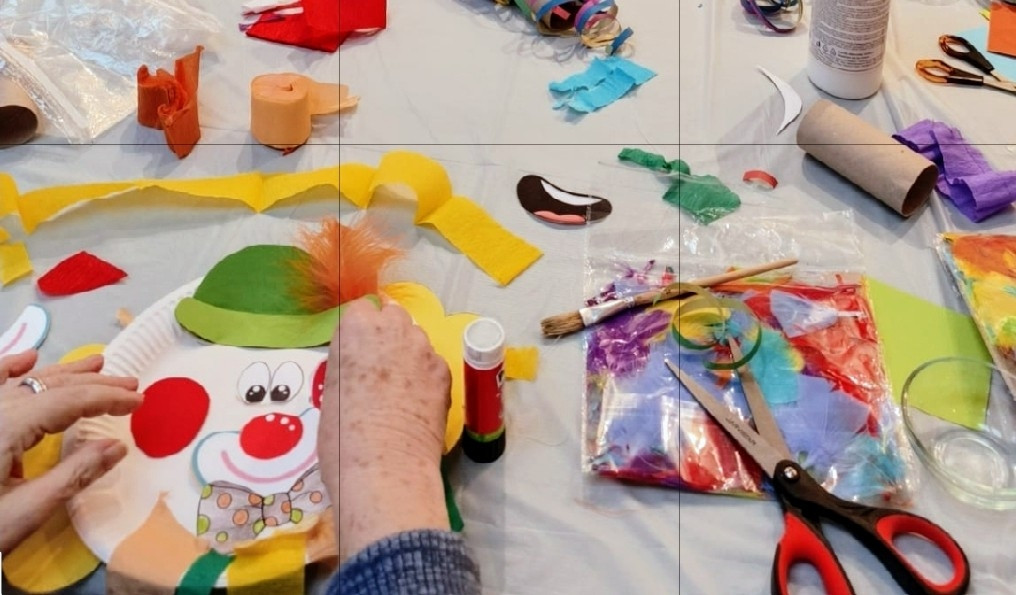 Bastelmaterialien und Hand beim Basteln eines Clowns aus Papier und Filz