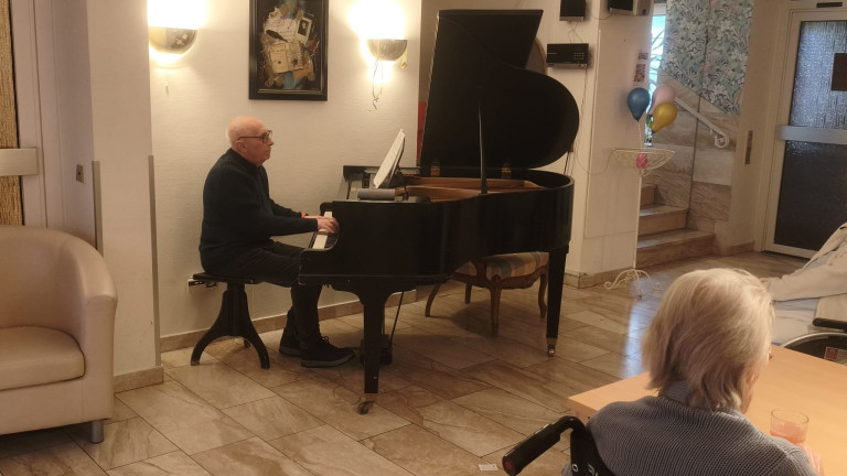 Pianist spielt auf einem Flügel in einem Wohnzimmer oder Veranstaltungsraum Älterer Mann spielt auf einem Flügel in einem gemütlichen Raum